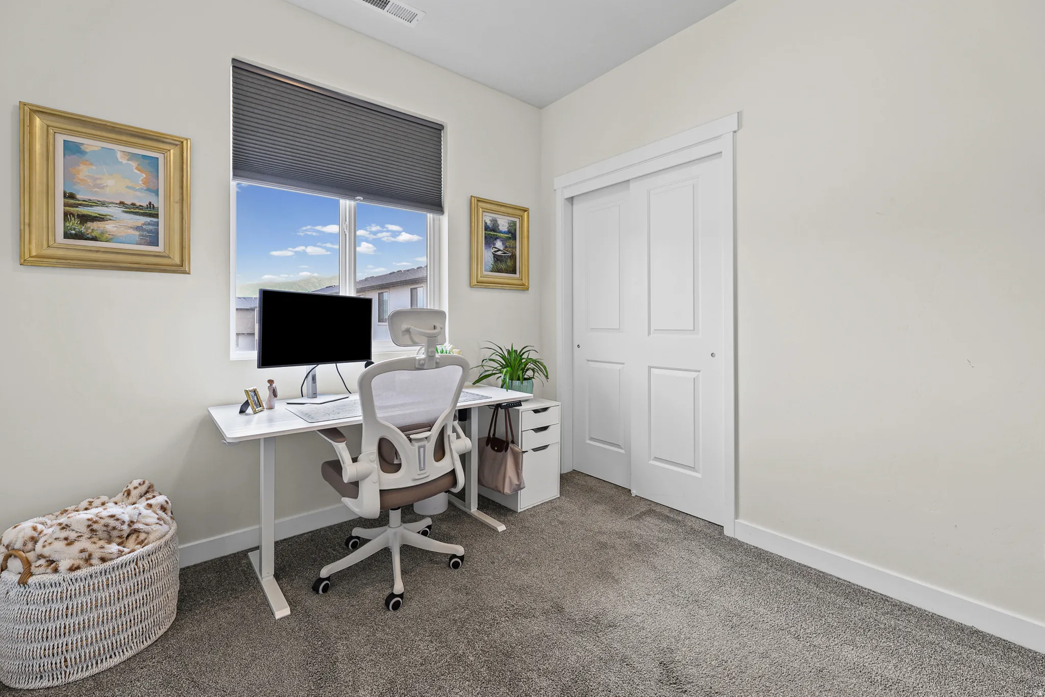 Carpeted room with a large window, a built-in closet with sliding panel doors, and white trim