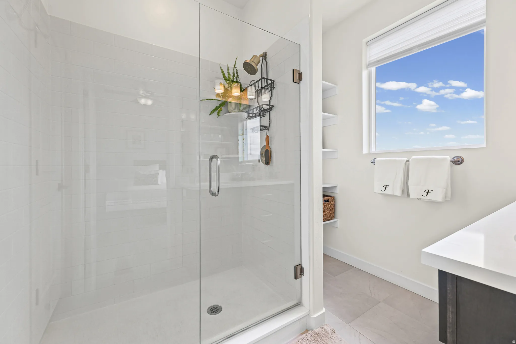 Glass-enclosed shower with white tiled walls and a bronze-finish showerhead