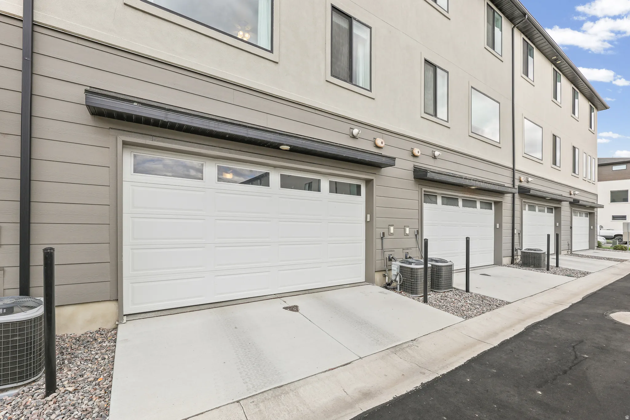 Attached garage with window inserts, concrete driveway, and gray siding exterior