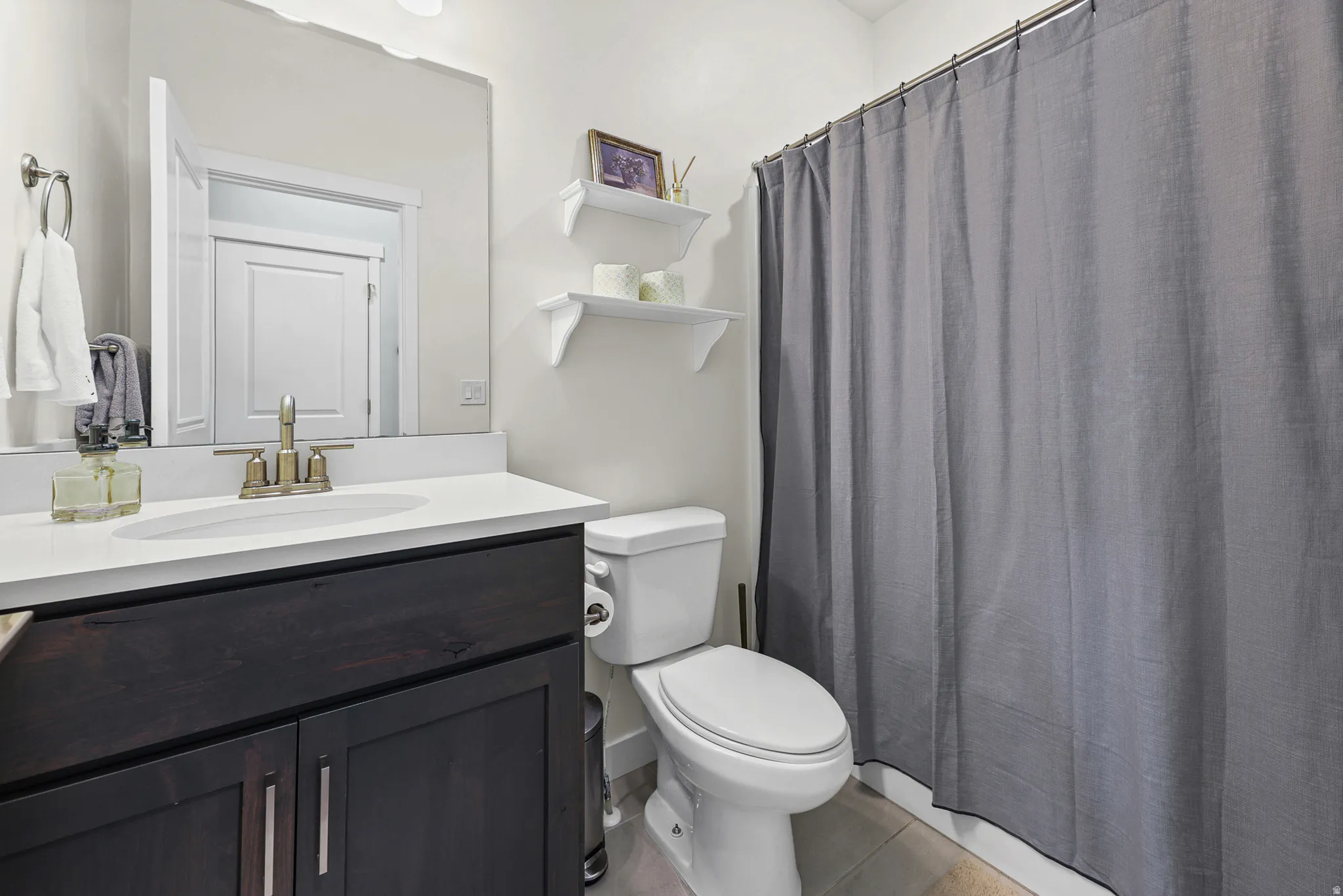 Dark wood-finish vanity with a white countertop and oval sink