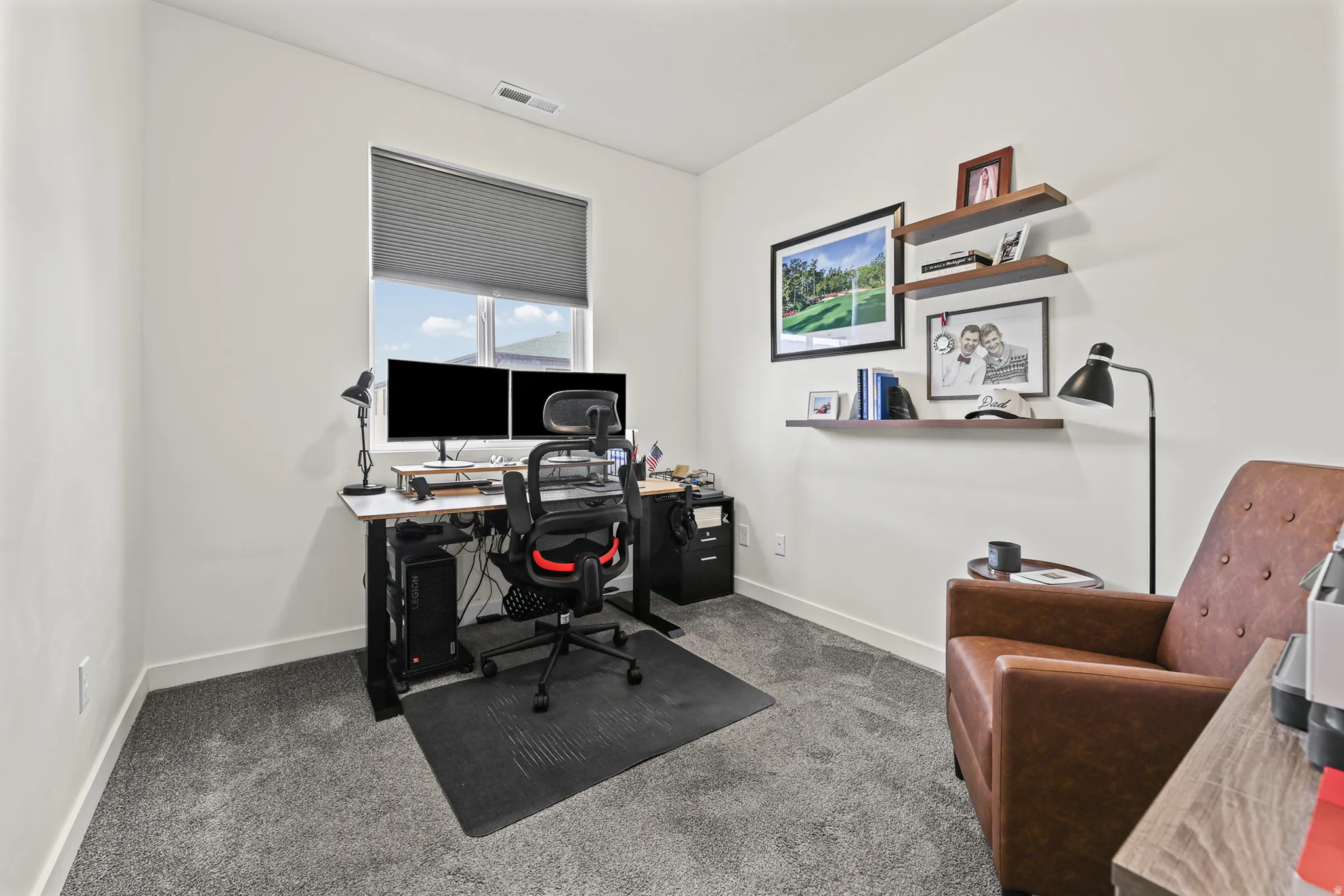Neutral wall paint, gray carpet flooring, window with a pull-down blind, and built-in floating shelves