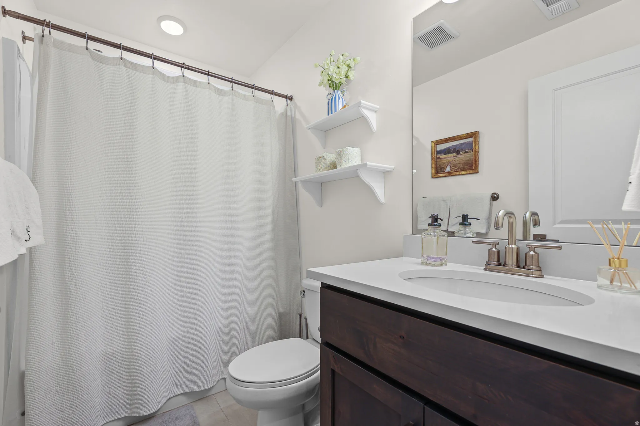 White shower curtain over a tub, toilet, and a vanity with a white countertop