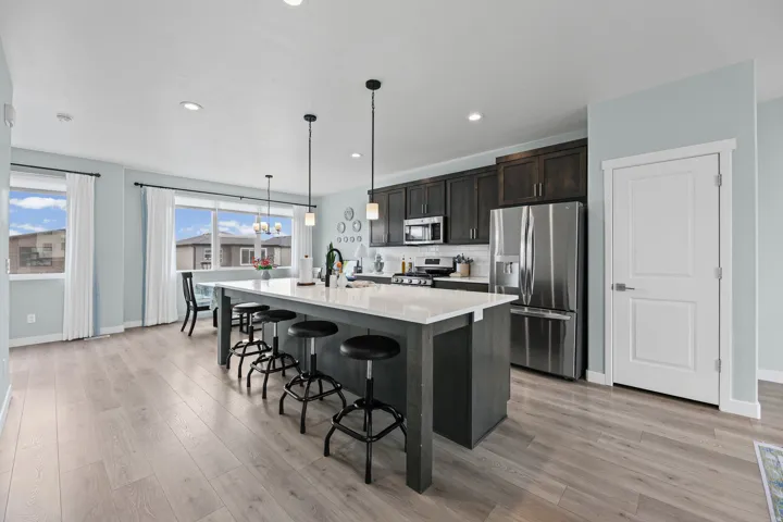 Kitchen featuring a large island with white countertop, dark wood-finish cabinetry, stainless steel appliances, and wood-finish flooring