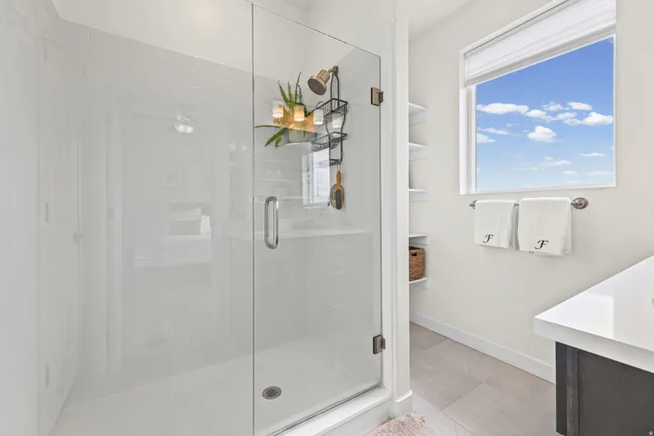 Glass-enclosed shower with white tiled walls and a bronze-finish showerhead