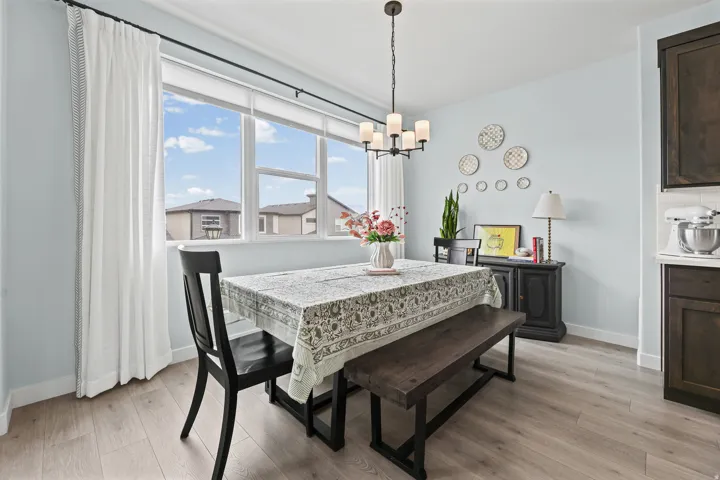 Expansive window with roller shade, wood-finish flooring, dark wood cabinetry, subway tile backsplash, and a modern chandelier