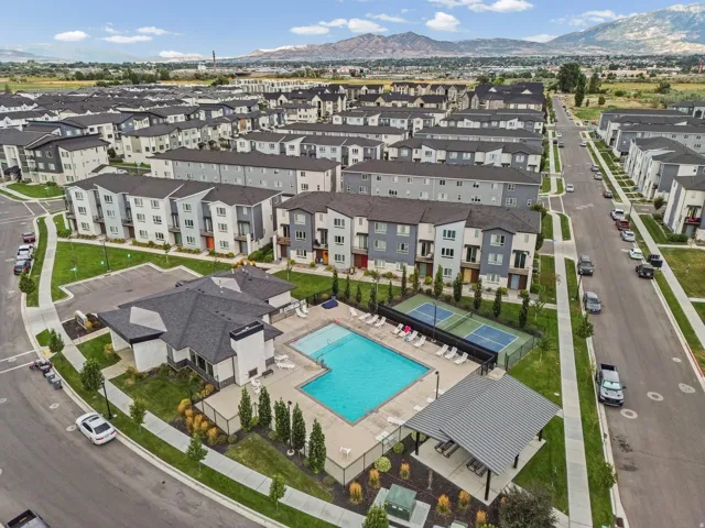 Community features a swimming pool, tennis court, communal building, covered outdoor seating area, and mountain backdrop