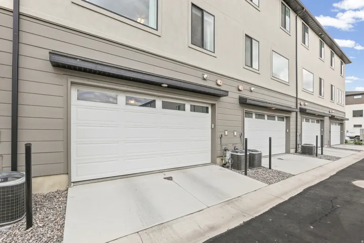 Attached garage with window inserts, concrete driveway, and gray siding exterior
