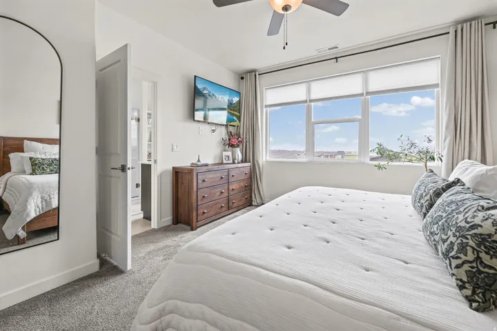 Carpeted room with a ceiling fan, a wall-mounted television, and a wood-finish dresser