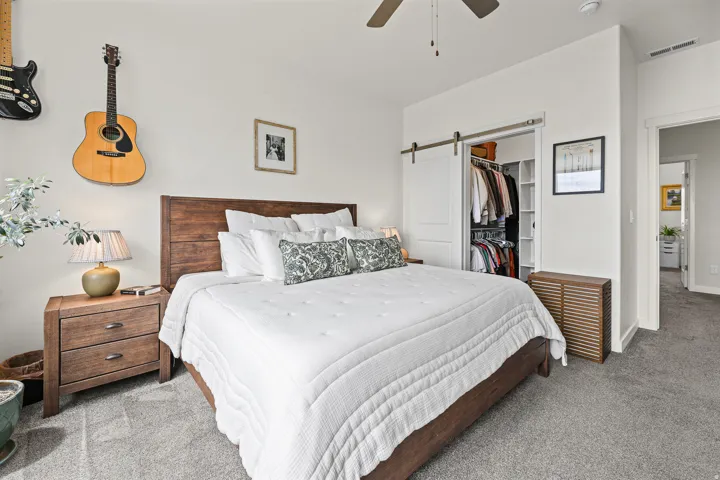 Bedroom featuring wall-to-wall carpeting, a wood-finish bed frame with headboard, and a ceiling fan