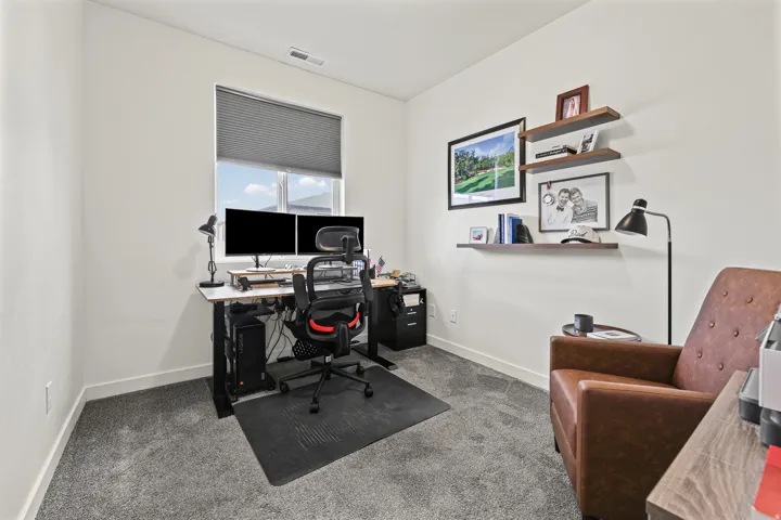 Neutral wall paint, gray carpet flooring, window with a pull-down blind, and built-in floating shelves