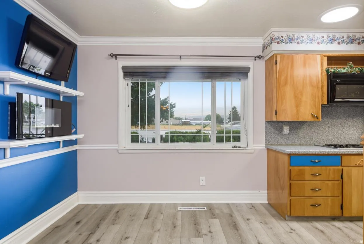 Wood-finish flooring, crown molding, double-hung window, built-in cabinetry, and overhead lighting