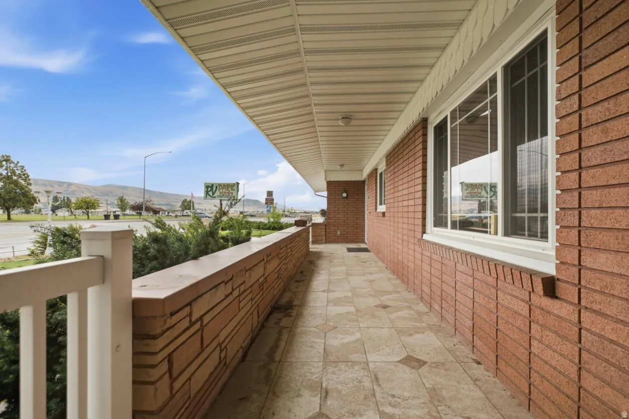 Brick exterior, covered walkway, tiled flooring with accent patterns, white railing, and multiple windows with grids