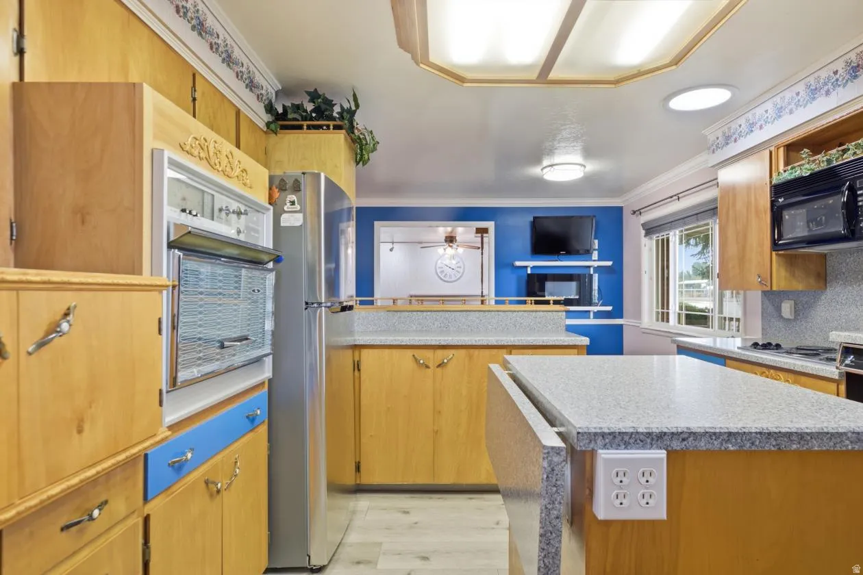 Kitchen featuring wood-finish cabinetry, light-toned countertops, built-in wall oven, and built-in microwave