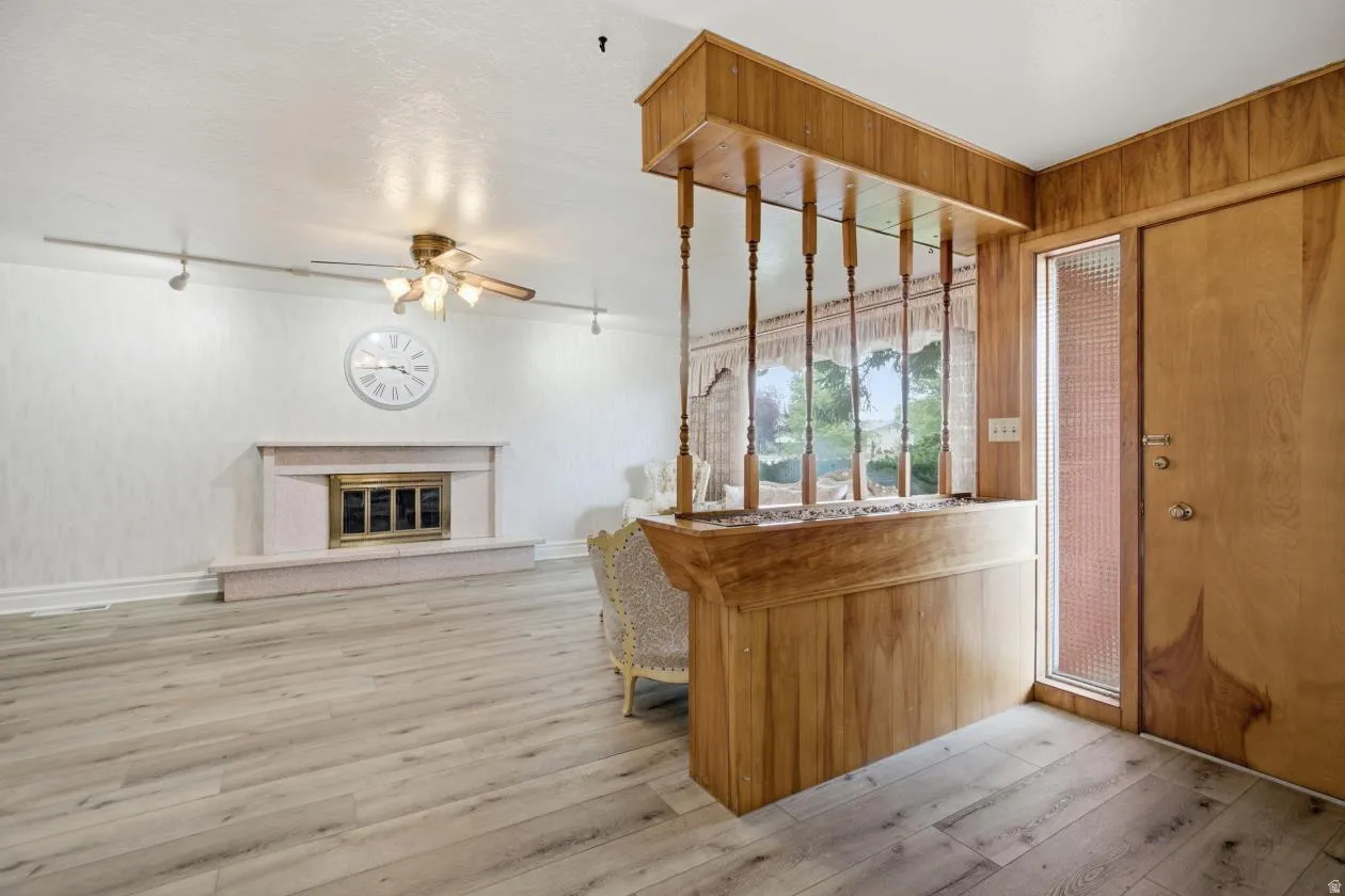 Wood-finish flooring, a white textured wall, and a fireplace with a decorative mantel and hearth