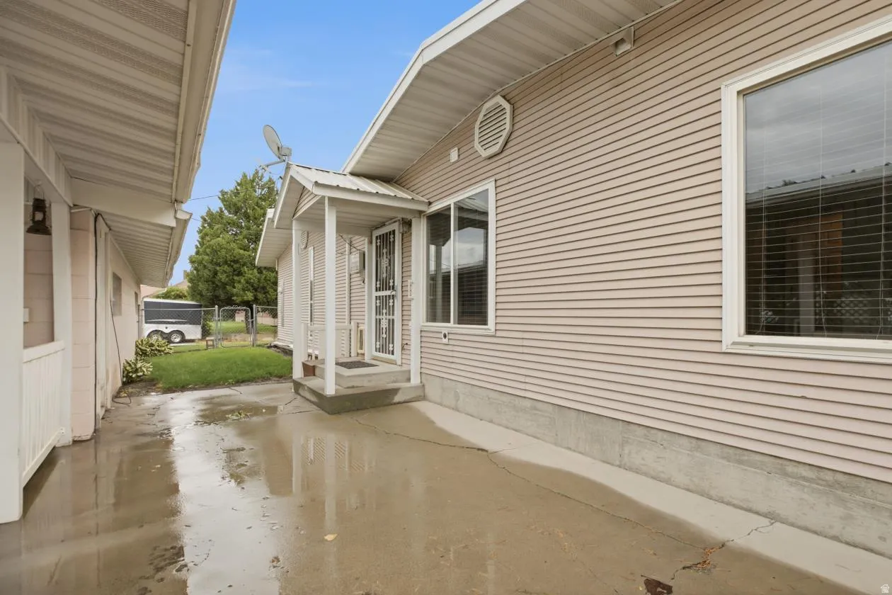 Siding exterior with multiple windows, covered entry porch, and concrete walkway between the backdoor and the detached garage/storage area