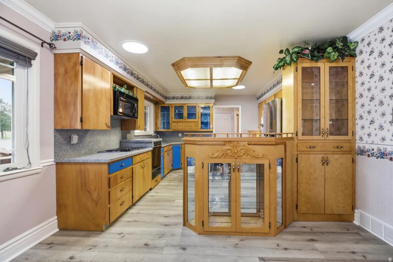 Kitchen featuring wood cabinetry, light wood-finish flooring, a built-in microwave, and integrated display cabinetry