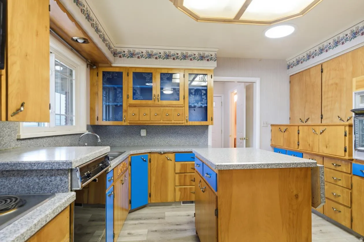 Kitchen featuring wood cabinetry with blue accents, light-toned countertops, and wood-finish flooring