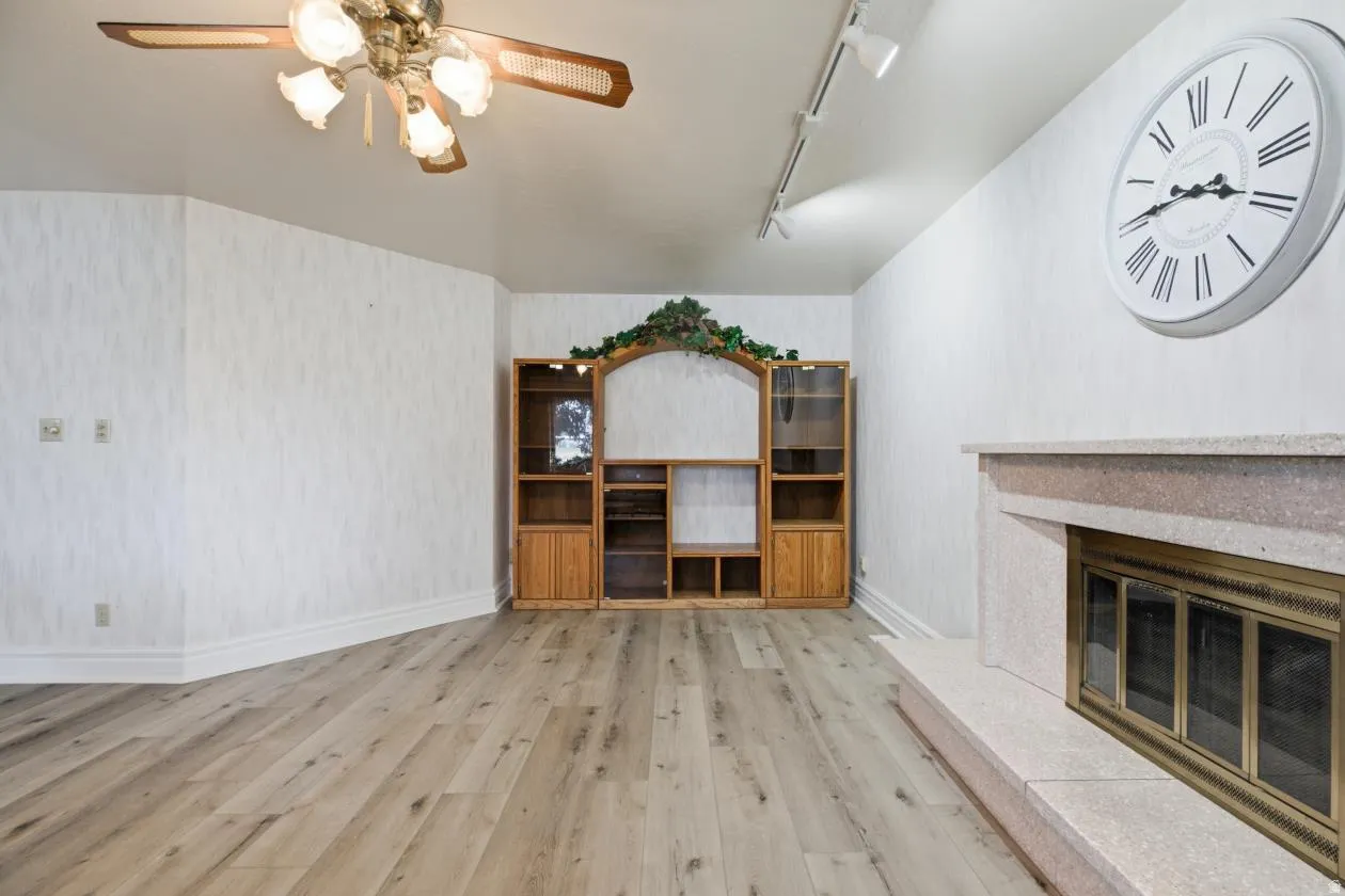 Wood-finish flooring, built-in entertainment center, ceiling fan, track lighting, and a stone-clad fireplace