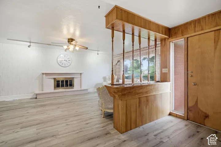 Wood-finish flooring, a white textured wall, and a fireplace with a decorative mantel and hearth