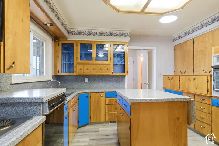 Kitchen featuring wood cabinetry with blue accents, light-toned countertops, and wood-finish flooring