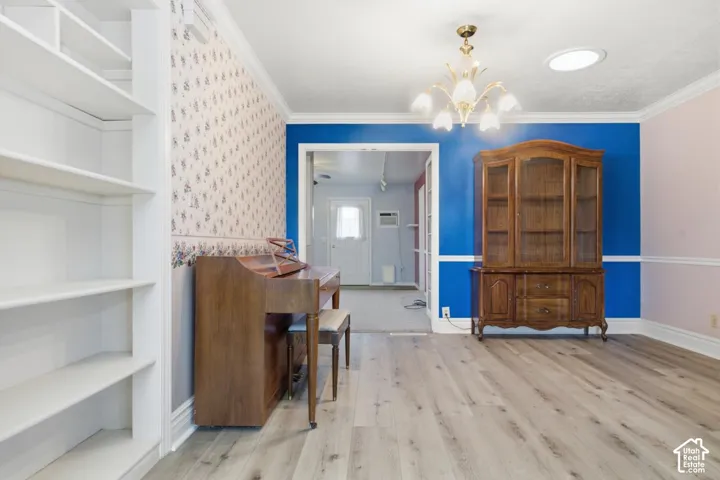 Wood-finish flooring, built-in shelving, crown molding, and an overhead chandelier