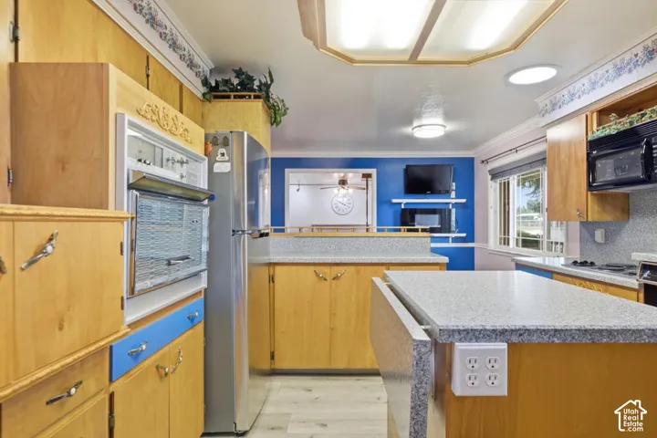 Kitchen featuring wood-finish cabinetry, light-toned countertops, built-in wall oven, and built-in microwave