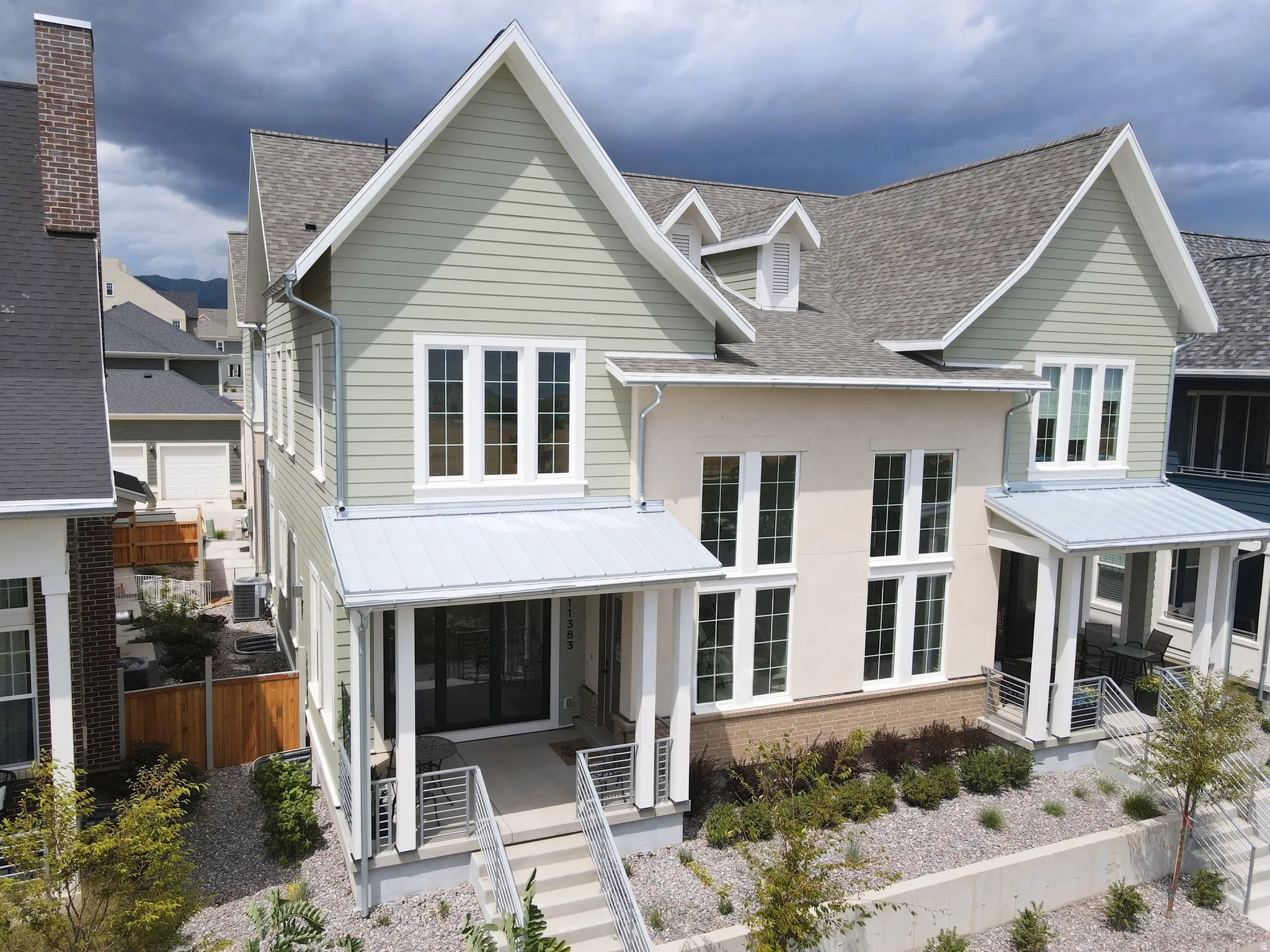 Modern farmhouse design featuring a crisp white exterior with horizontal siding, steeply pitched gable rooflines, and multiple dormer windows