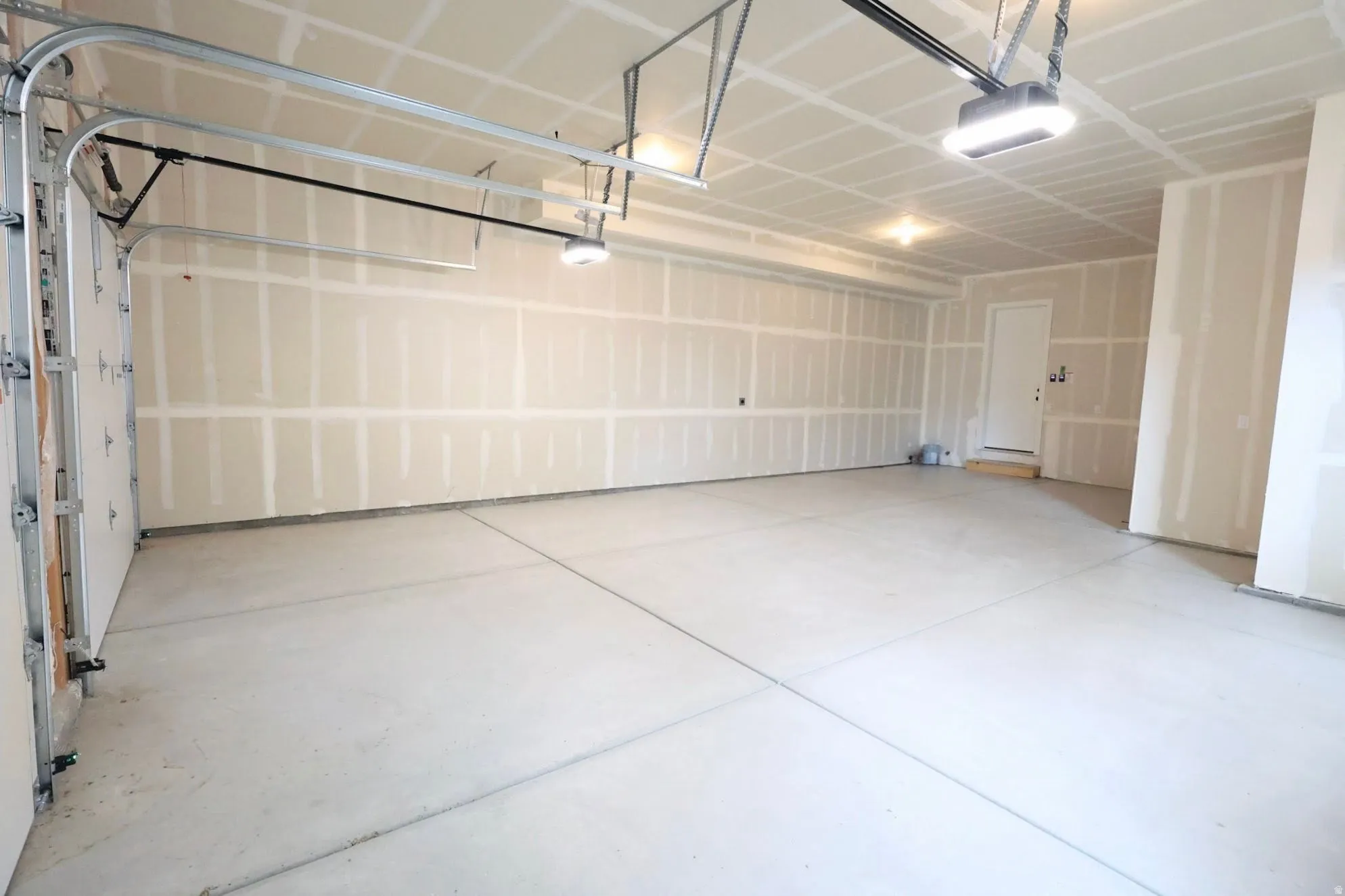 Concrete flooring, built-in overhead lighting, and an overhead garage door mechanism