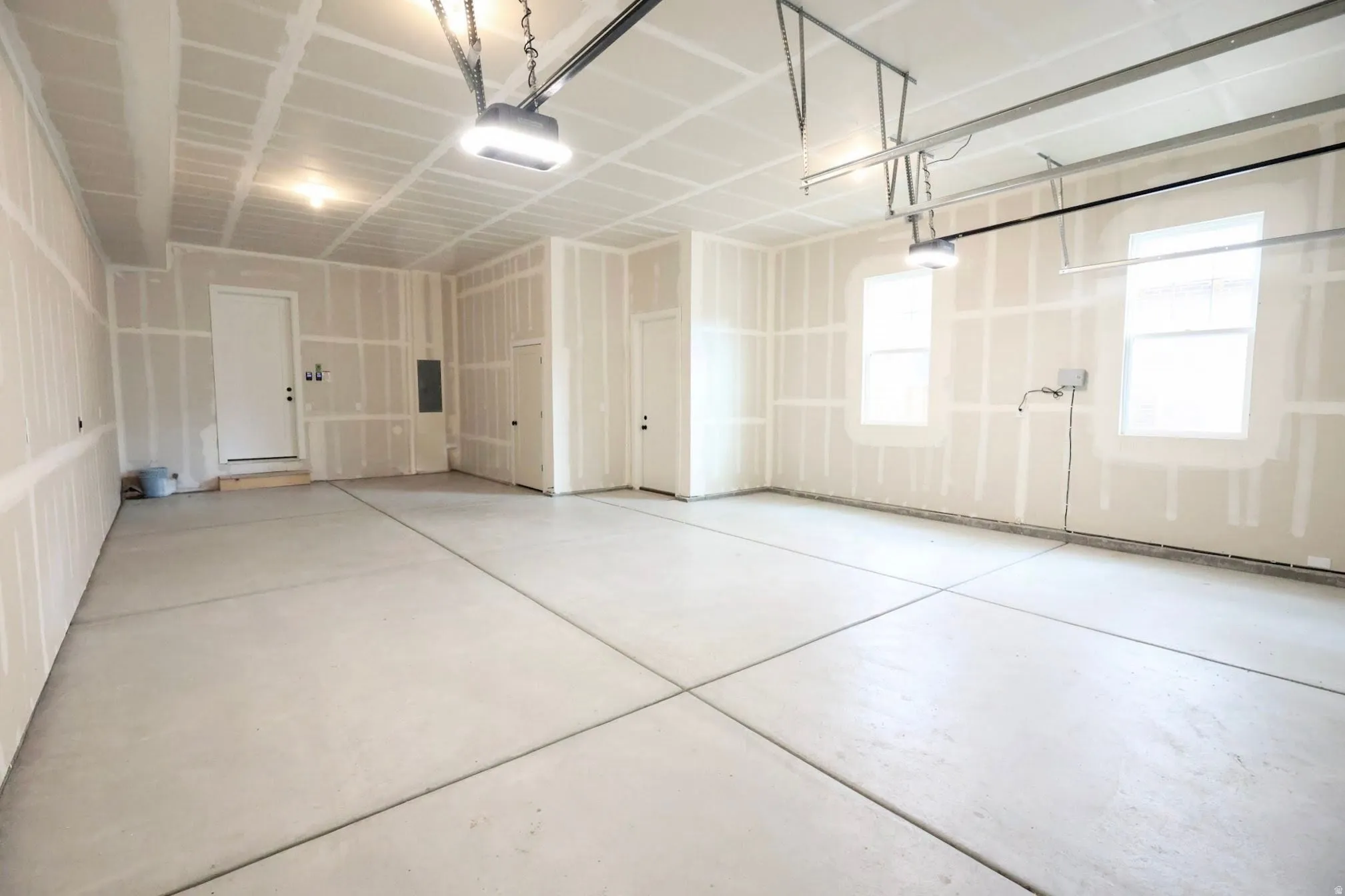 Spacious garage with concrete flooring, two windows, and two overhead garage door openers