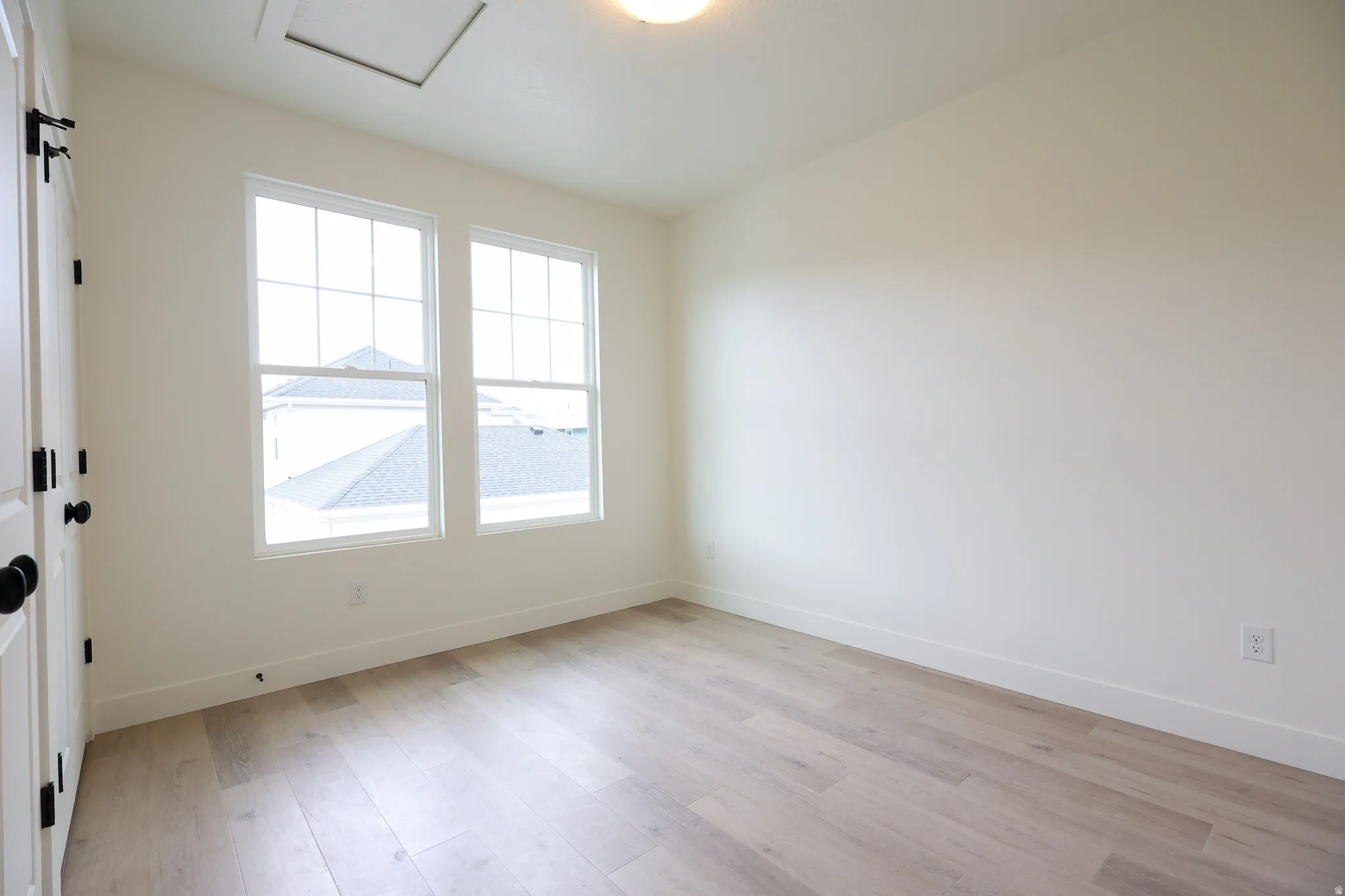 ADU-Light wood-finish flooring, two large windows with grid patterns, and an overhead lighting fixture