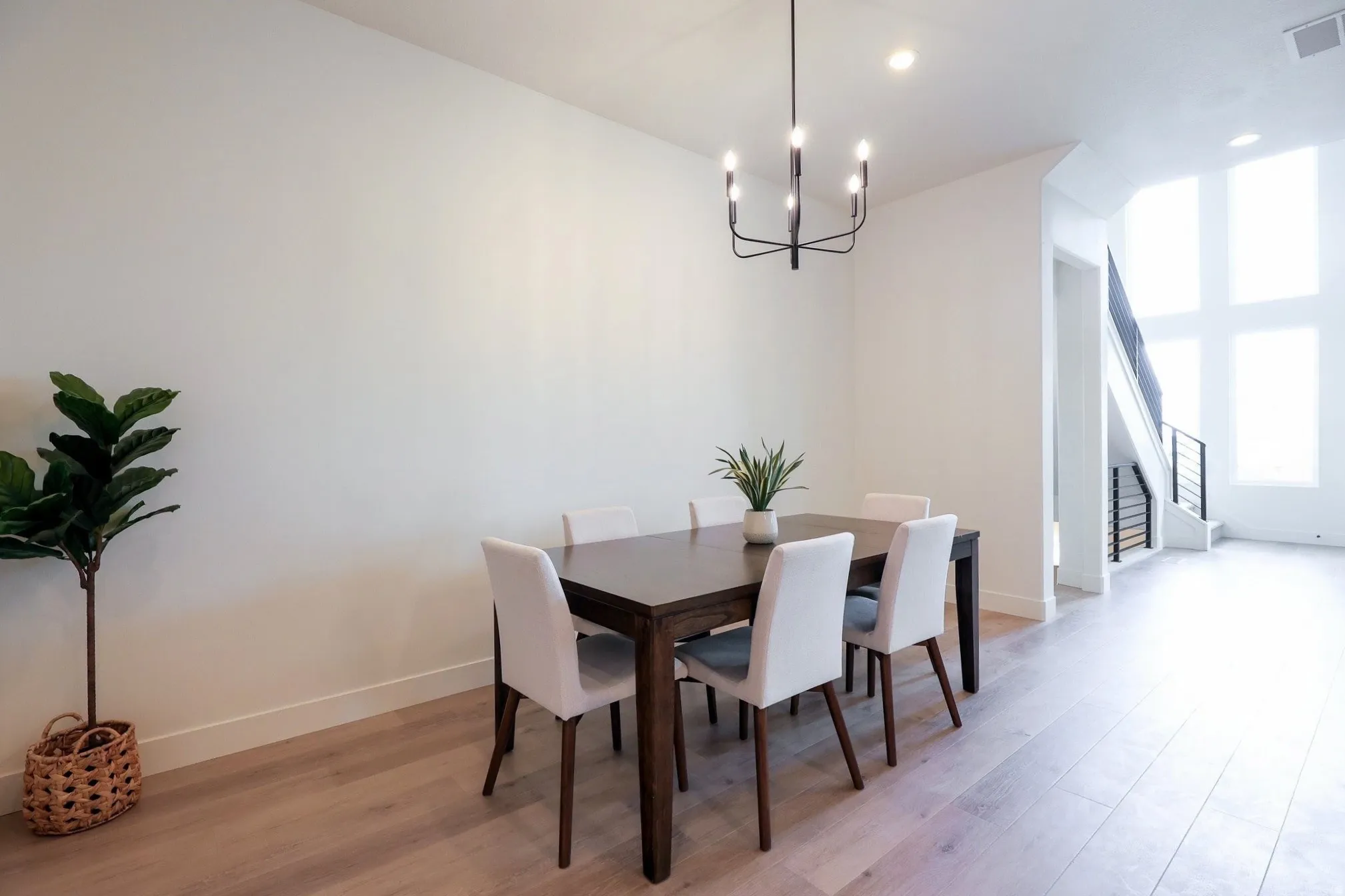 Dining area featuring wood-finish flooring, a contemporary chandelier, and high ceilings