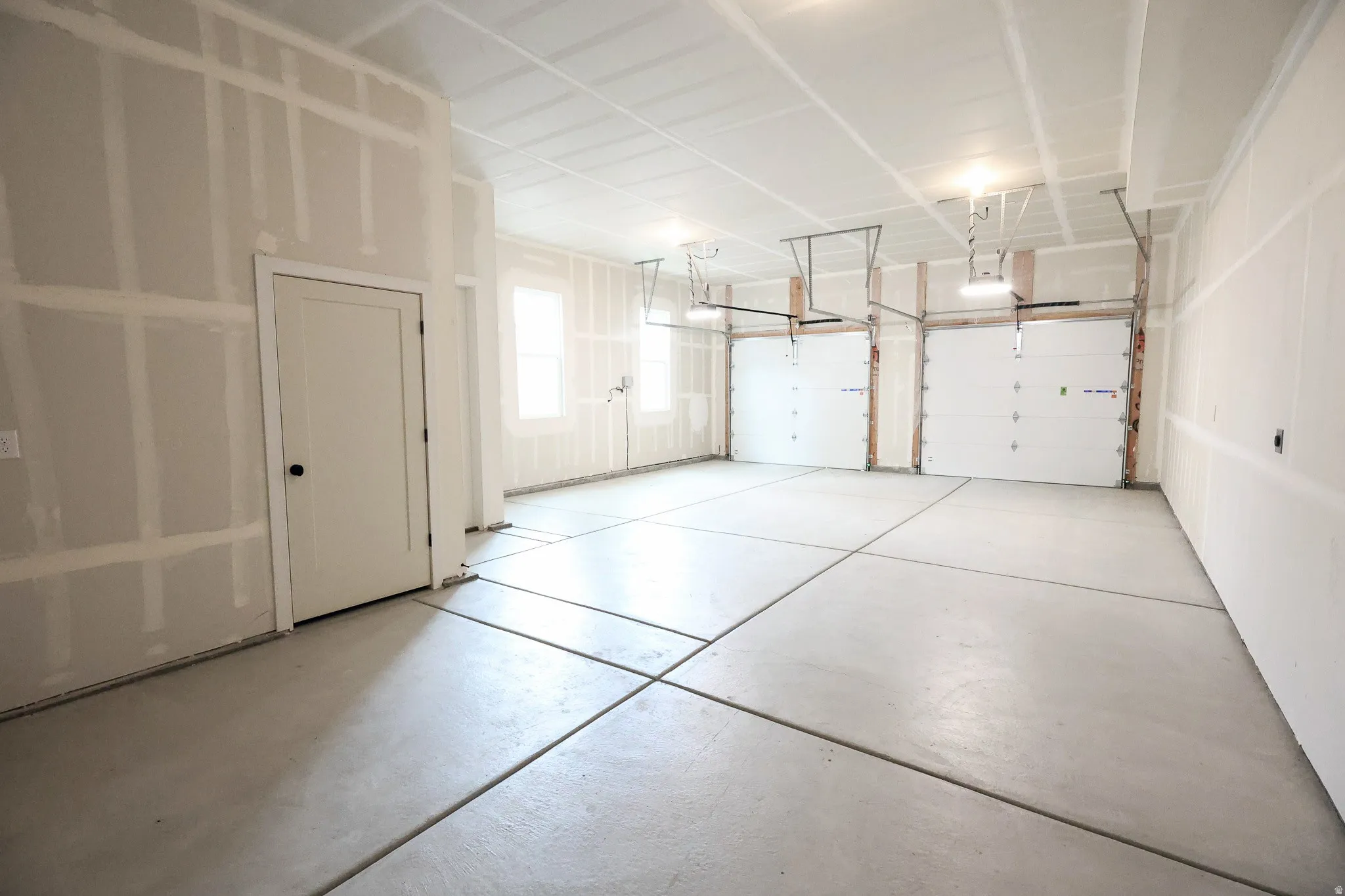 Three car garage, two windows providing natural light, and a concrete floor