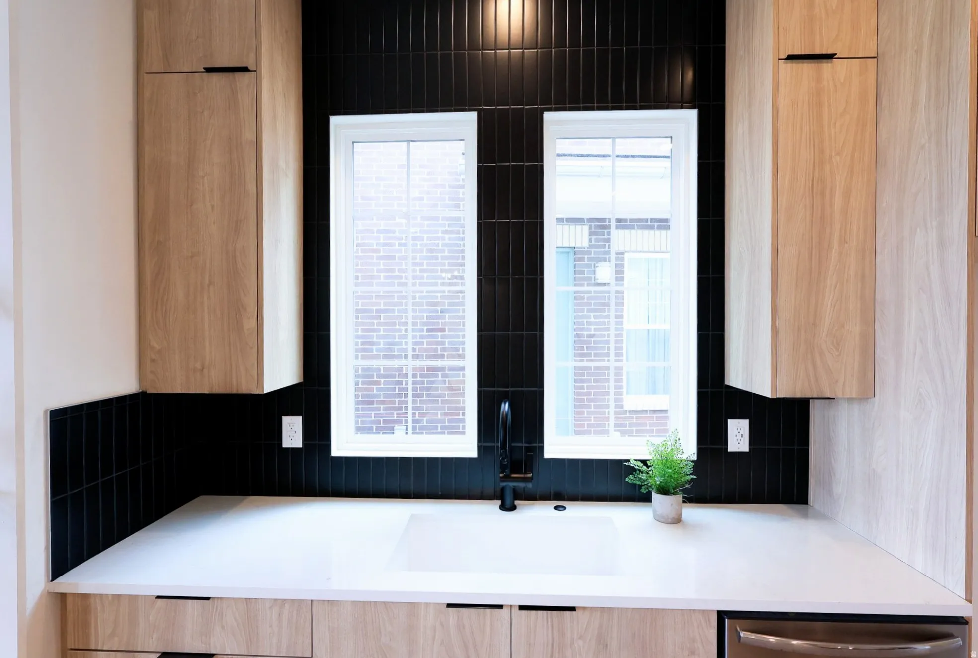Sleek black subway tile backsplash paired with light wood-finish cabinetry