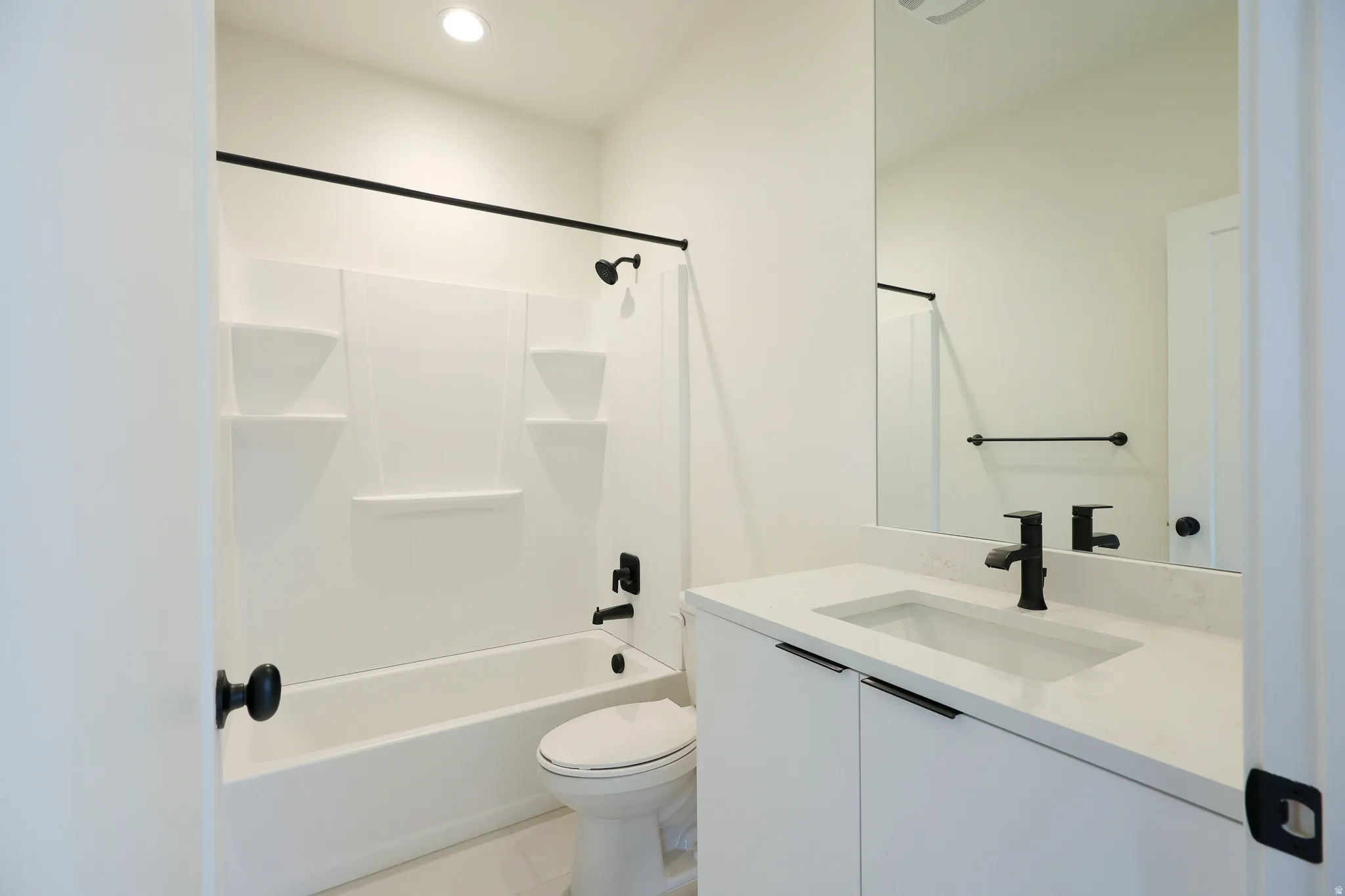 ADU-White vanity with integrated sink, sleek black hardware, and a framed mirror