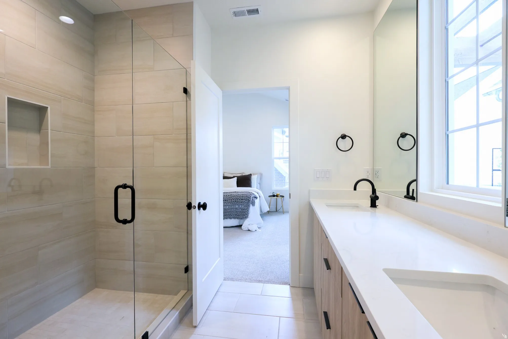 Primary bathroom - Dual vanity with undermount sinks and matte black fixtures, full-width mirror, and a window with grid detailing