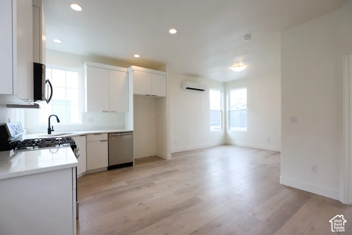 ADU-Kitchen featuring white cabinetry, light countertops, stainless steel dishwasher, gas range, and wood-finish flooring
