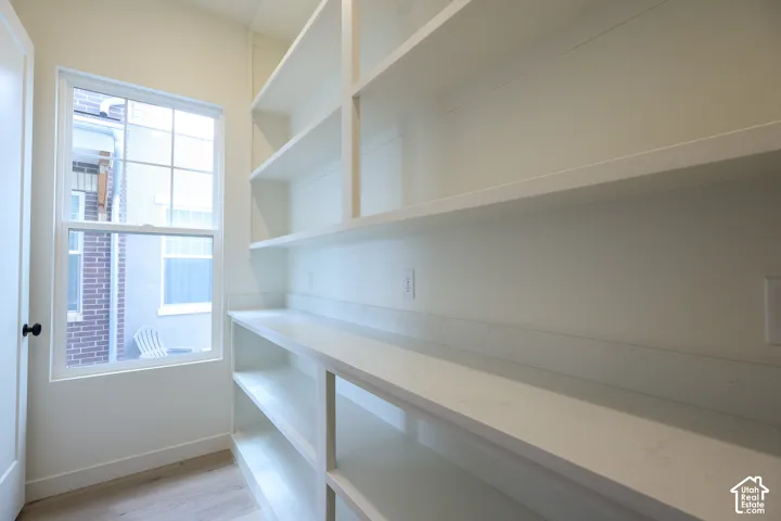 Built-in shelving with multiple storage levels, a window for natural illumination, and light wood-finish flooring