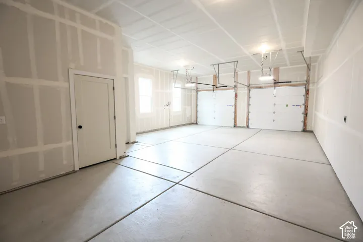 Three car garage, two windows providing natural light, and a concrete floor