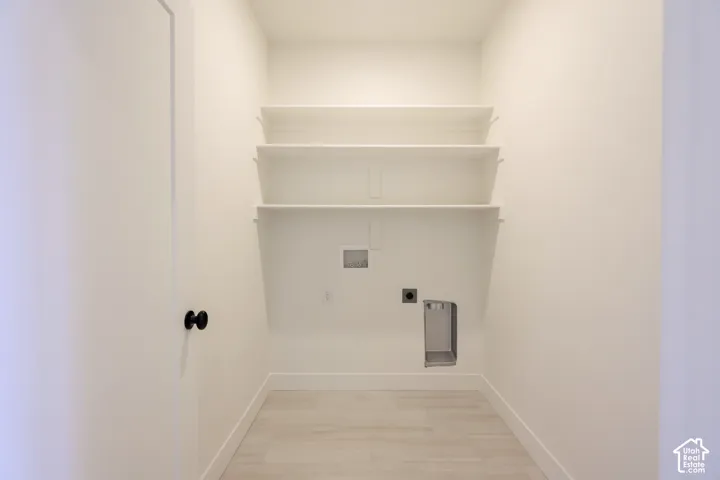 Utility closet featuring built-in shelving, light-toned tile flooring, and utility hookups