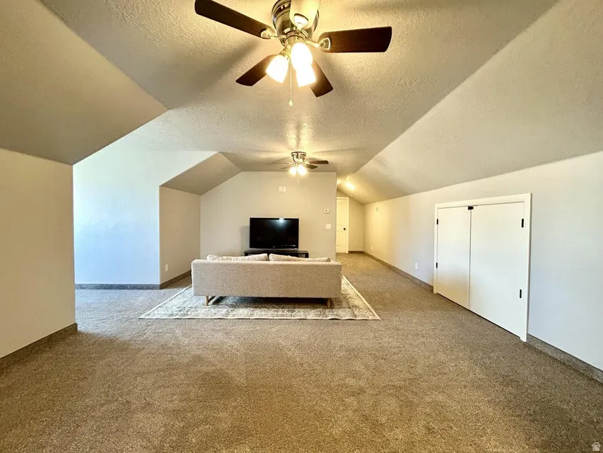 Expansive carpeted room featuring vaulted ceilings, recessed lighting, and multiple ceiling fans