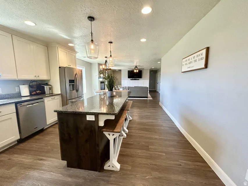 Kitchen with white cabinetry, granite countertops, and stainless steel appliances