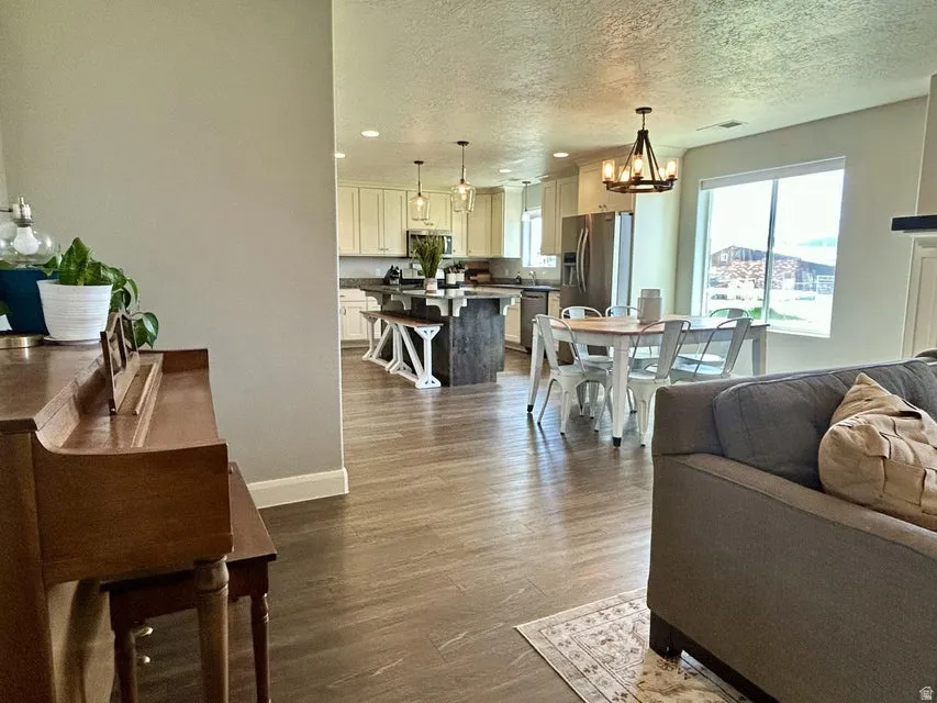Expansive kitchen featuring a large island, pendant lighting, stainless steel appliances, and wood-finish flooring throughout