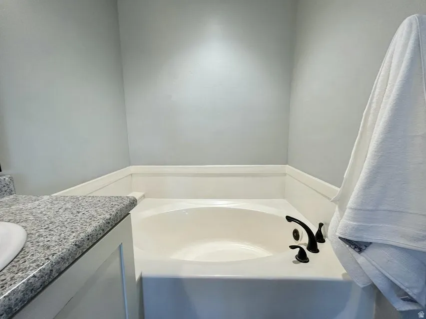 Built-in soaking tub with dark-toned fixtures and a light-toned surround