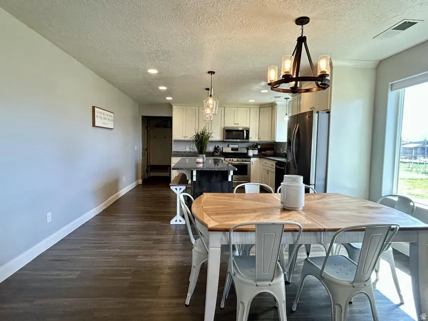 Open-concept dining area with wood-finish flooring, a contemporary chandelier, and recessed lighting