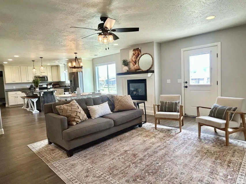 Wood-finish flooring throughout, featuring a fireplace with a white mantel, recessed lighting, and a ceiling fan