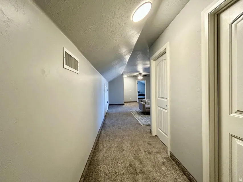 Carpeted hallway with light gray walls, white panel doors, and recessed ceiling lighting