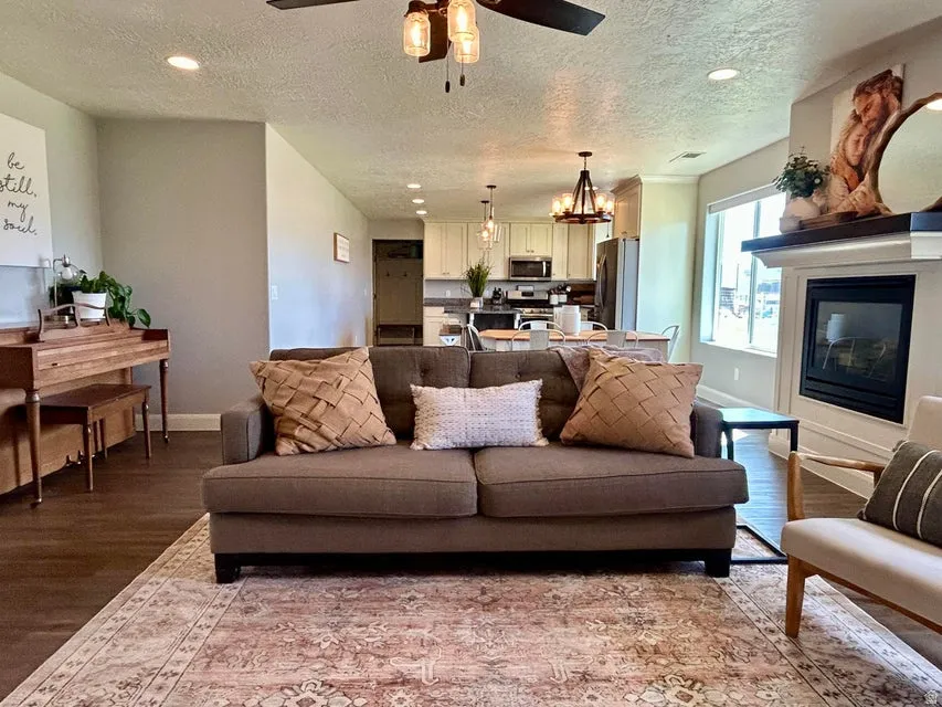 Recessed lighting, wood-finish flooring, and a fireplace with a white mantle