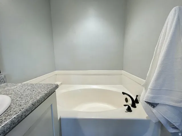 Built-in soaking tub with dark-toned fixtures and a light-toned surround