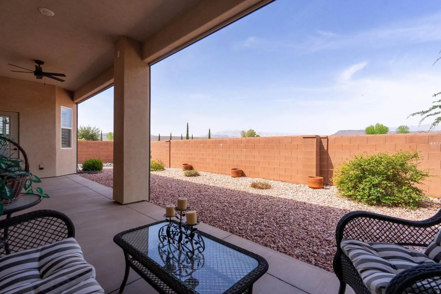 Covered patio with a ceiling fan, concrete flooring, and an exterior door