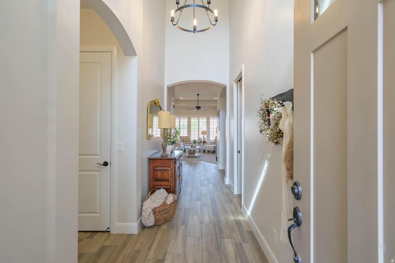 Vaulted entry with wood-finish flooring, arched doorways, and a circular chandelier